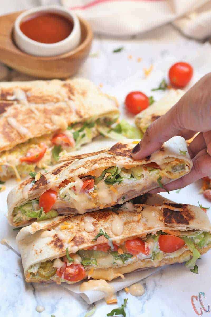 Vegetarian Homemade Crunchwrap Supreme Recipe - Refried beans, cheese sauce, crunchy tostadas, sour cream, chopped lettuce, diced tomatoes, Jalapenos and shredded cheese all wrapped inside a large burrito tortilla and then pan roasted until perfectly golden brown in color.