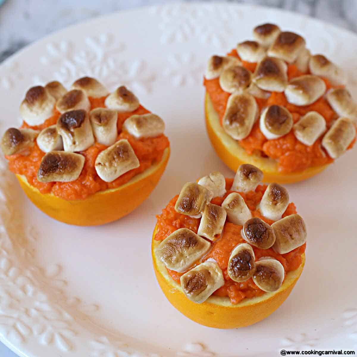 Loaded sweet potatoes in orange cups with marshmallows.