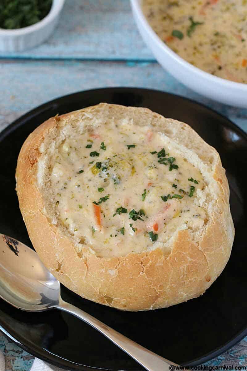 Homemade Bread bowl served with broccoli cheese soup on a black plate